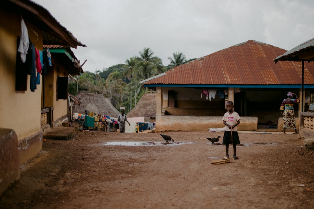 woman in pink shirt and black pants standing on brown sand during daytime