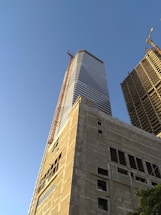 A construction site showing workers collaborating on building a modern commercial structure under a clear sky.