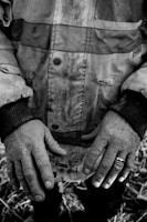 Close-up of rugged hands gripping reins, with a backdrop of worn denim and dusty boots.