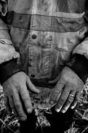 Close-up of rugged hands gripping reins, with a backdrop of worn denim and dusty boots.