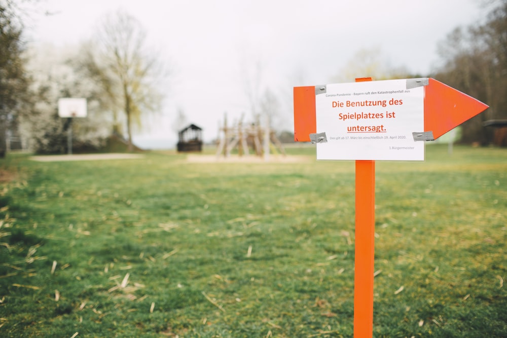 orange and white road sign on green grass field during daytime