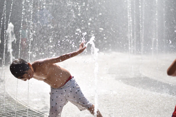 A child sliding down the Crown Cascade water slide, water sparkling in the sunlight.