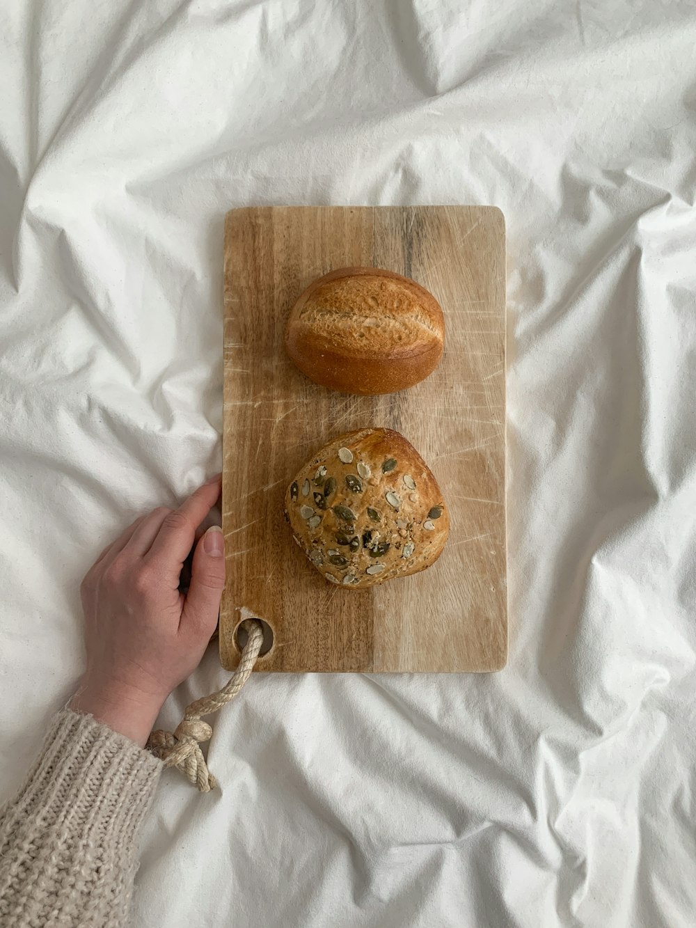 person holding brown wooden chopping board