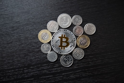 Close-up of a vintage brass bitcoin token resting on a wooden desk beside a notebook filled with handwritten notes.