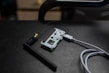 A small electronic circuit board is connected to an antenna and a USB cable. The board features various electronic components and connectors, and it is resting on a dark, textured surface.