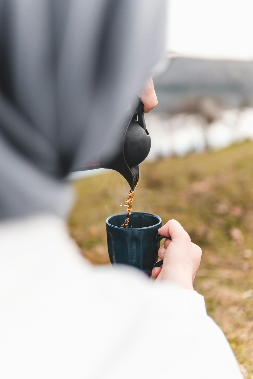 person holding black ceramic mug with yellow flower