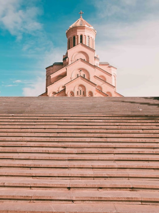 white concrete building under blue sky during daytime in Tbilisi St. Trinity Cathedral Georgia