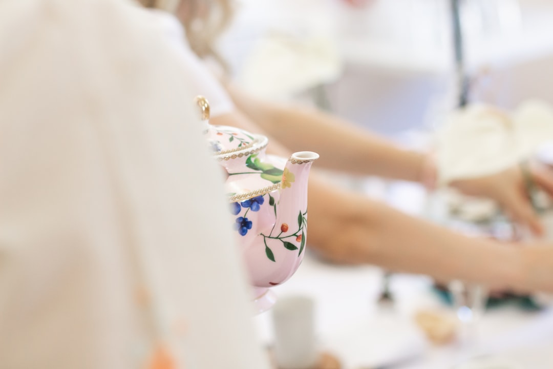 woman in white floral dress holding white and blue floral ceramic teapot