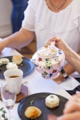 person holding white and blue floral ceramic mug