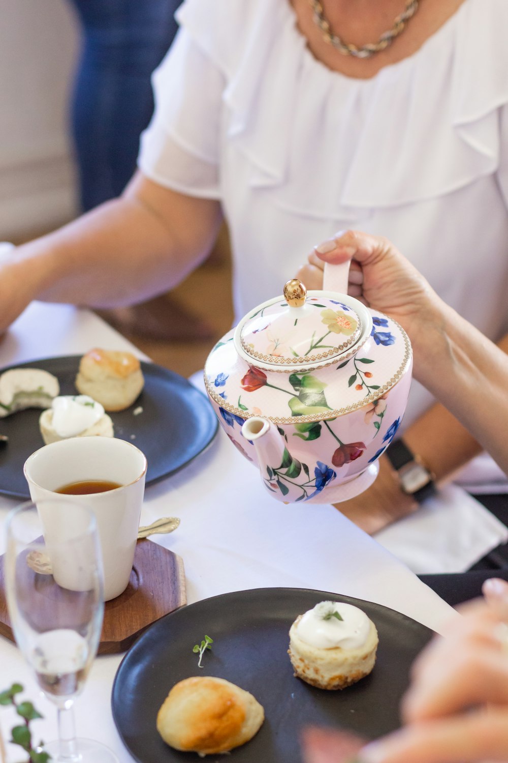 person holding white and blue floral ceramic mug