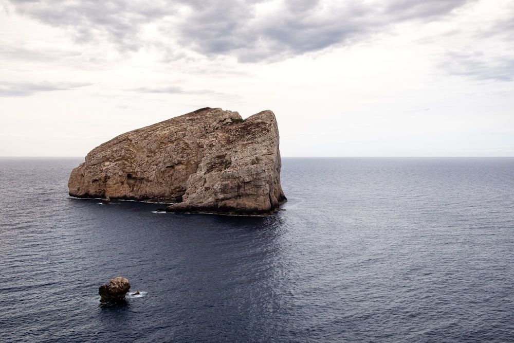 brown rock formation on body of water during daytime