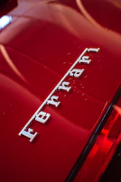 Close-up of a glossy red Ferrari F8 Spider with reflections of palm trees.