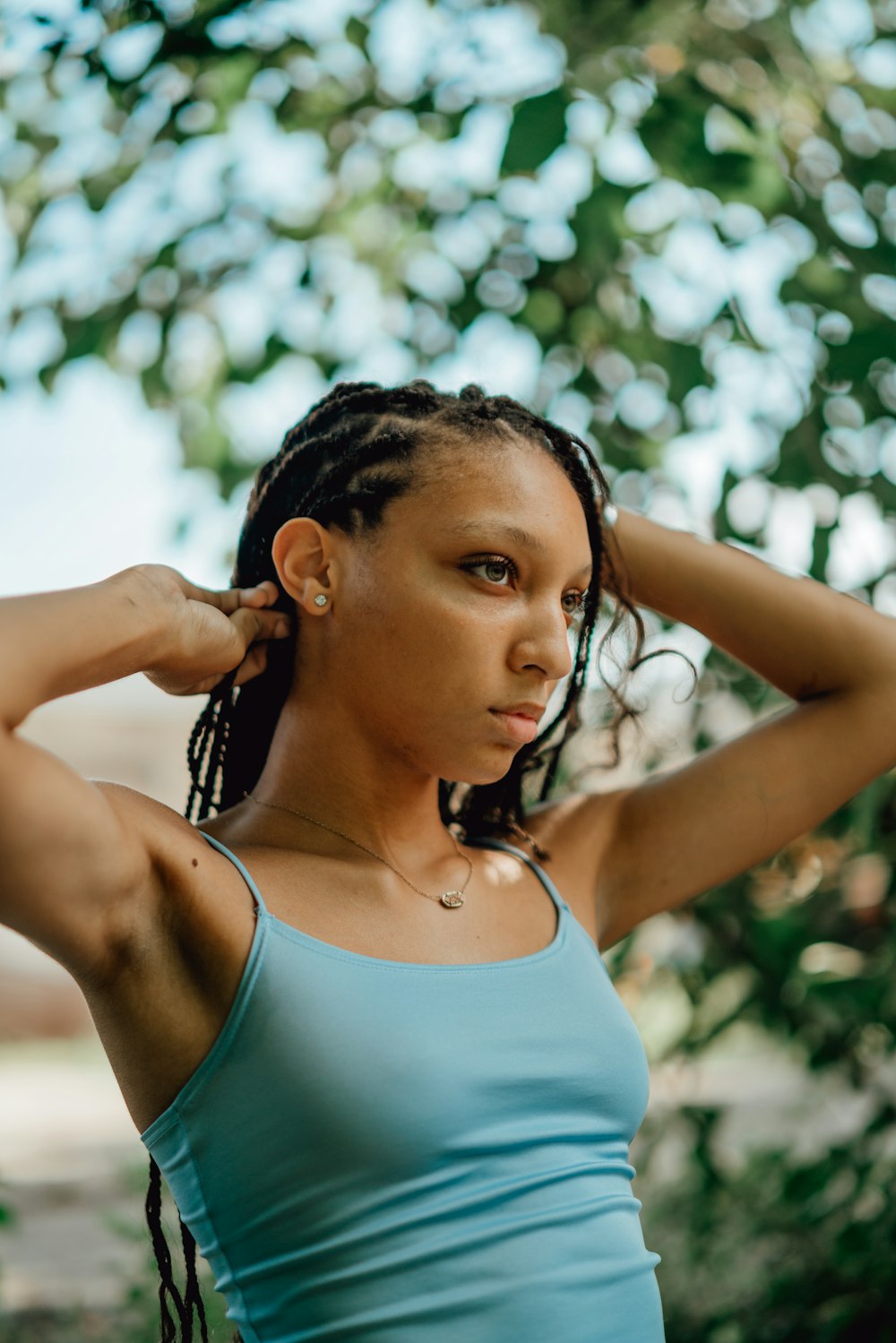 woman in teal tank top holding her hair