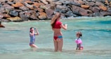 A family enjoying a sunny beach day, all wearing matching waterproof swim gear.