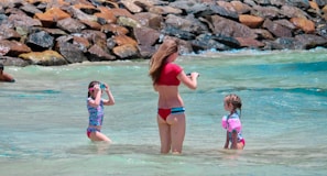 A family enjoying a sunny beach day, all wearing matching waterproof swim gear.