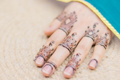Close-up of a hand adorned with intricate, freshly applied henna designs in warm brown tones.