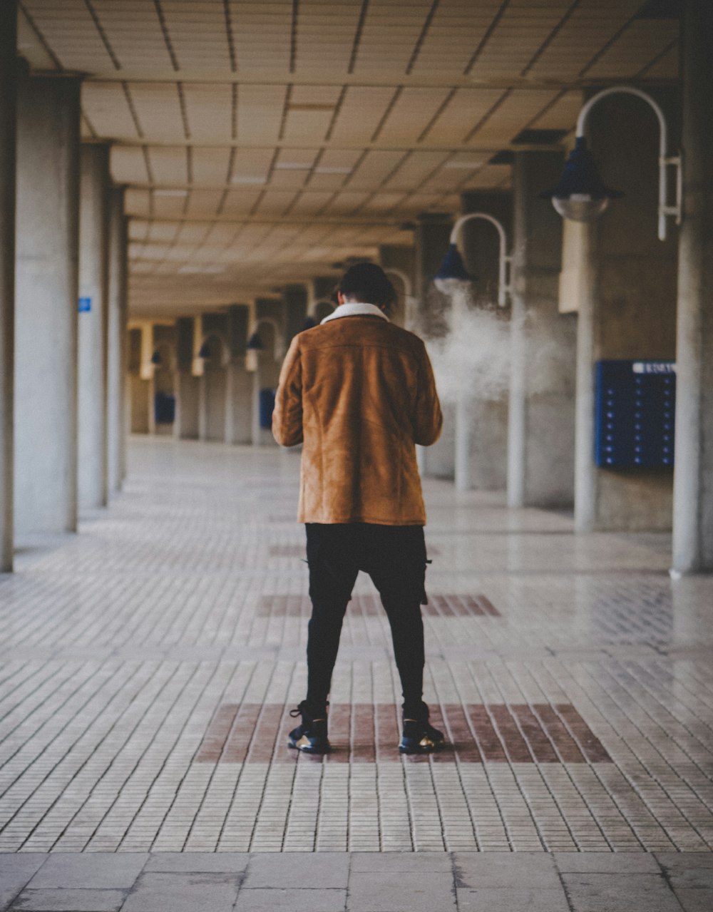 person in brown coat walking on sidewalk during daytime