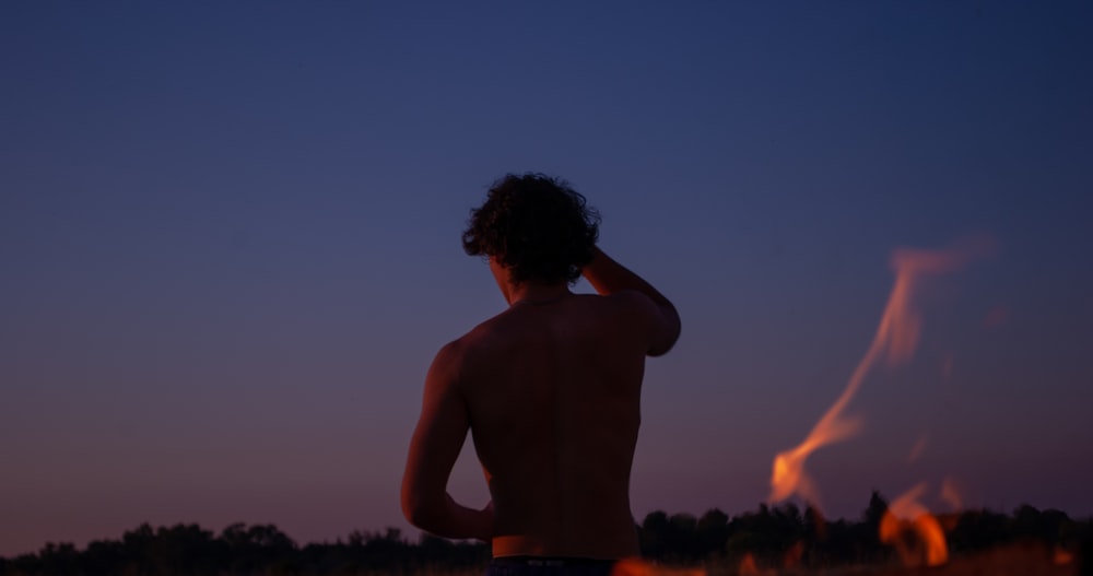 topless man standing during sunset