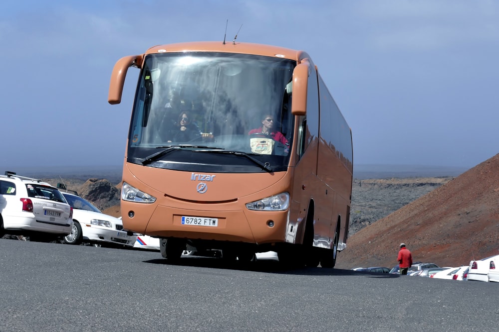 Bus orange et noir sur route asphaltée grise pendant la journée