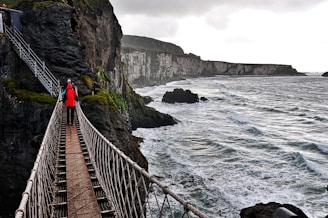 person in red jacket walking on wooden bridge