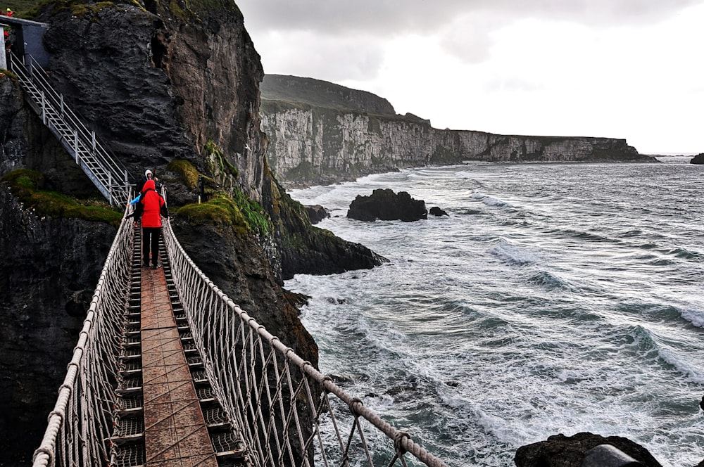 person in red jacket walking on wooden bridge