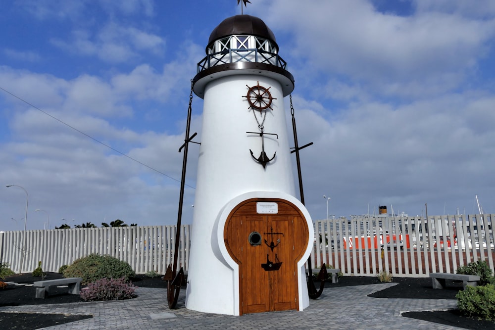 Phare blanc et brun sous un ciel nuageux pendant la journée