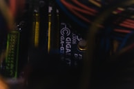 Close-up view of a computer motherboard with visible Gigabyte branding, featuring various components like RAM sticks and wiring. The image is dimly lit, adding a moody and technical ambiance.