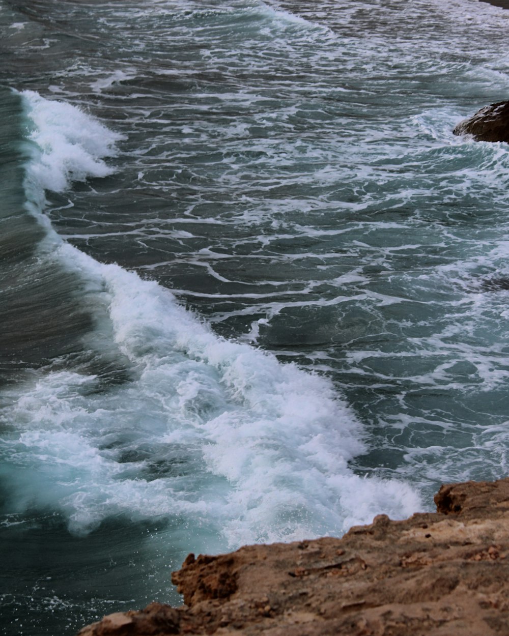 Les vagues de l’océan s’écrasent sur le rivage rocheux brun pendant la journée