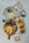 A breakfast or brunch spread on a marble table with two cups of latte art coffee, a plate with an egg and salad, croissants filled with salad and eggs, and a wooden serving board with scrambled eggs, bread, sausages, a hash brown, and some greens.