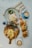 A breakfast or brunch spread on a marble table with two cups of latte art coffee, a plate with an egg and salad, croissants filled with salad and eggs, and a wooden serving board with scrambled eggs, bread, sausages, a hash brown, and some greens.