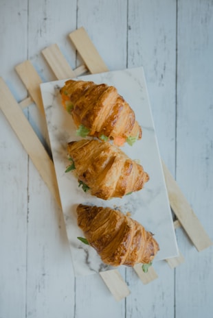 An assortment of golden croissants arranged neatly on a ceramic plate with earthy tones.