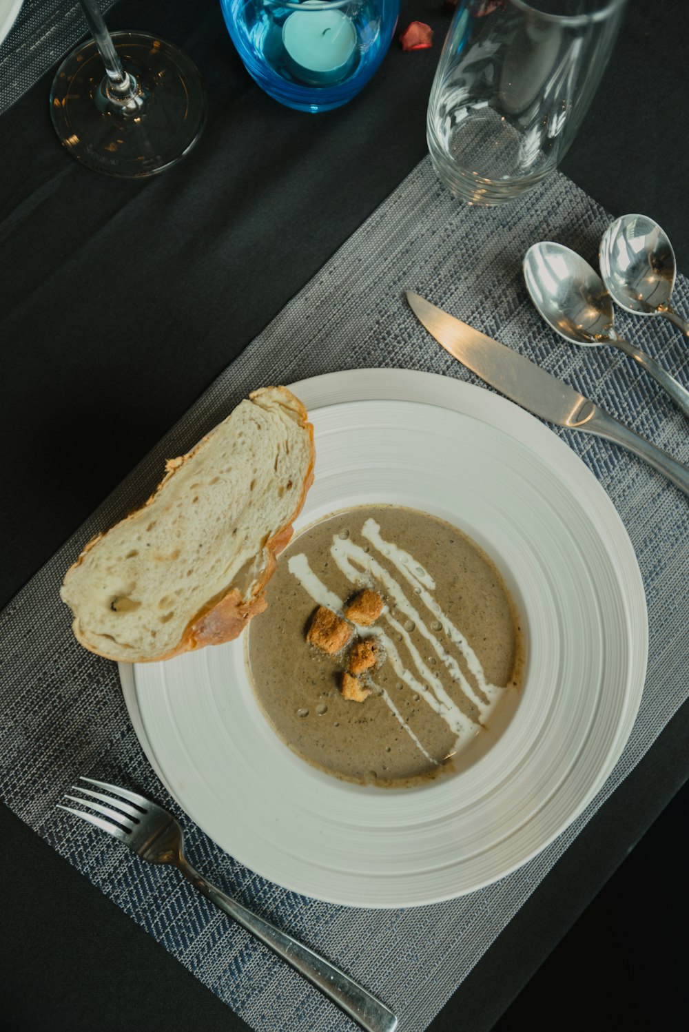 bread on white ceramic plate beside silver fork and knife