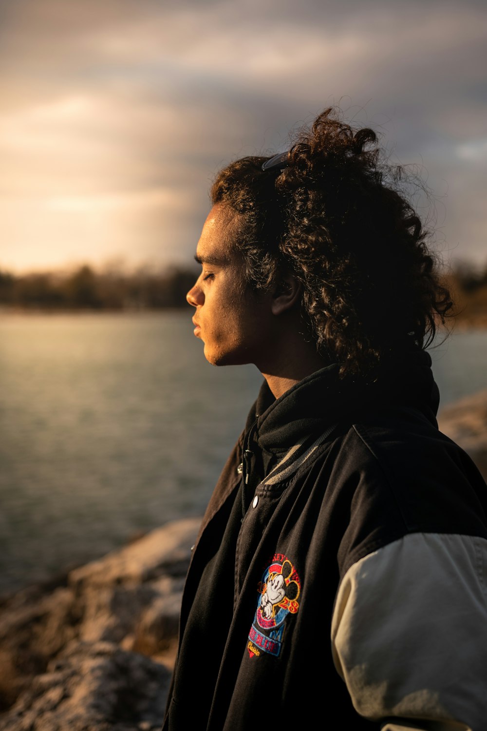 man in black jacket standing near body of water during daytime