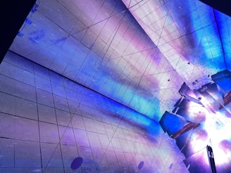 Detail of metallic ceiling panels reflecting electric blue accents in a modern office space.