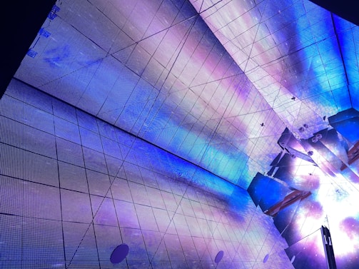 Detail of metallic ceiling panels reflecting electric blue accents in a modern office space.