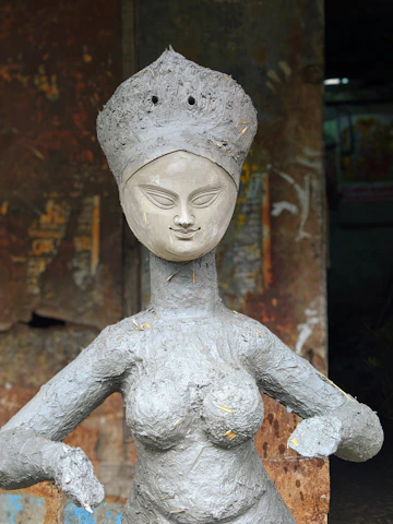 Clay sculpture of a woman in traditional dress holding a basket, reflecting indigenous roots.