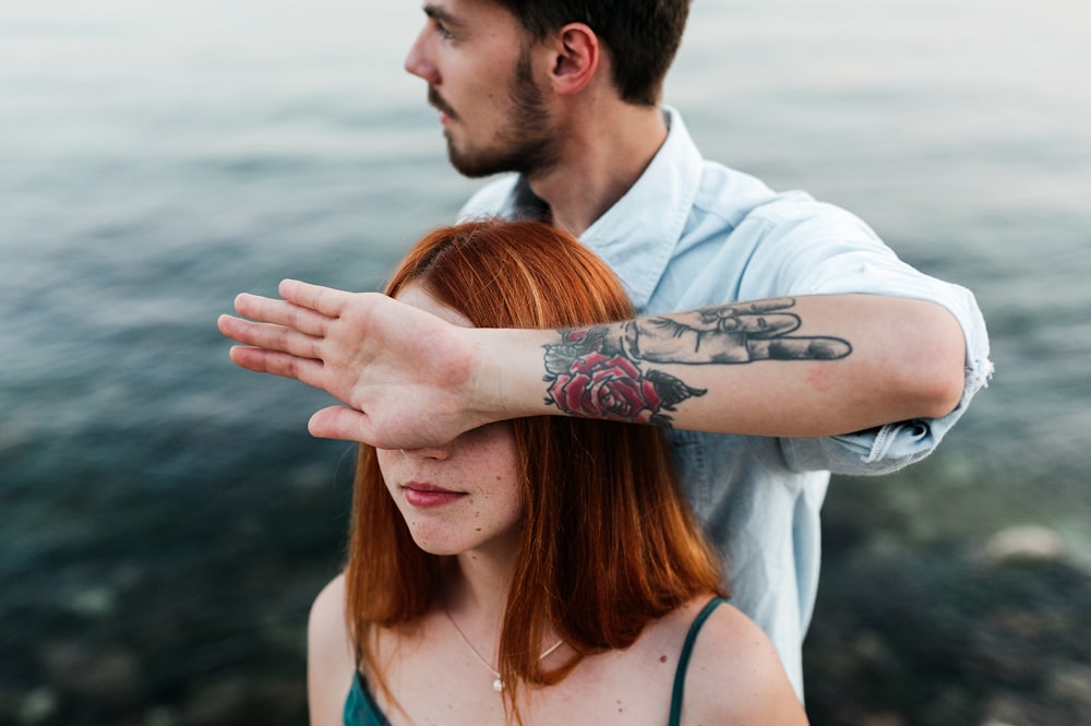 man in white dress shirt with tattoo on womans left cheek