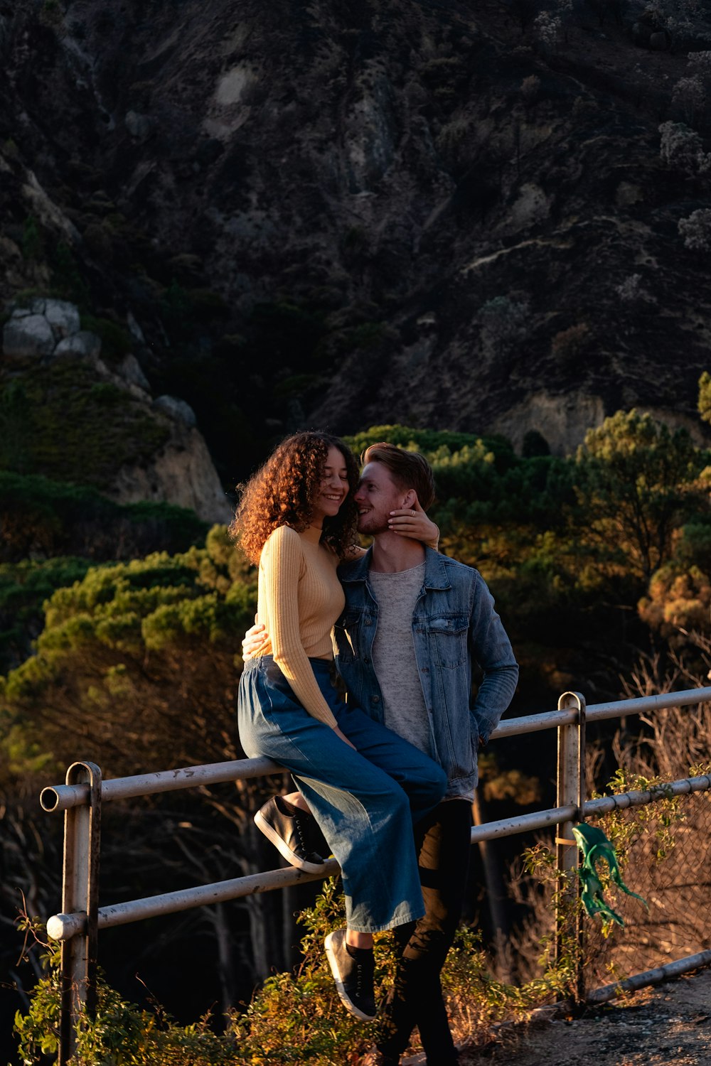 couple kissing on gray metal railings during daytime