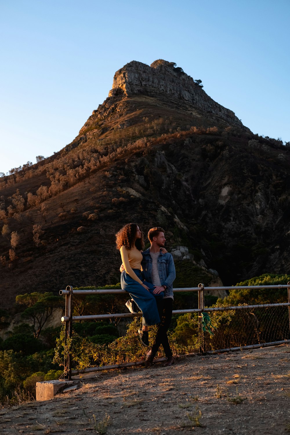 woman in pink long sleeve shirt sitting on brown wooden railings near brown rock formation during