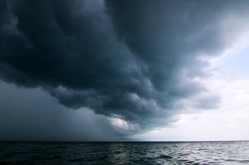 Dark storm clouds gathering low over open Caribbean-blue ocean water, no people visible