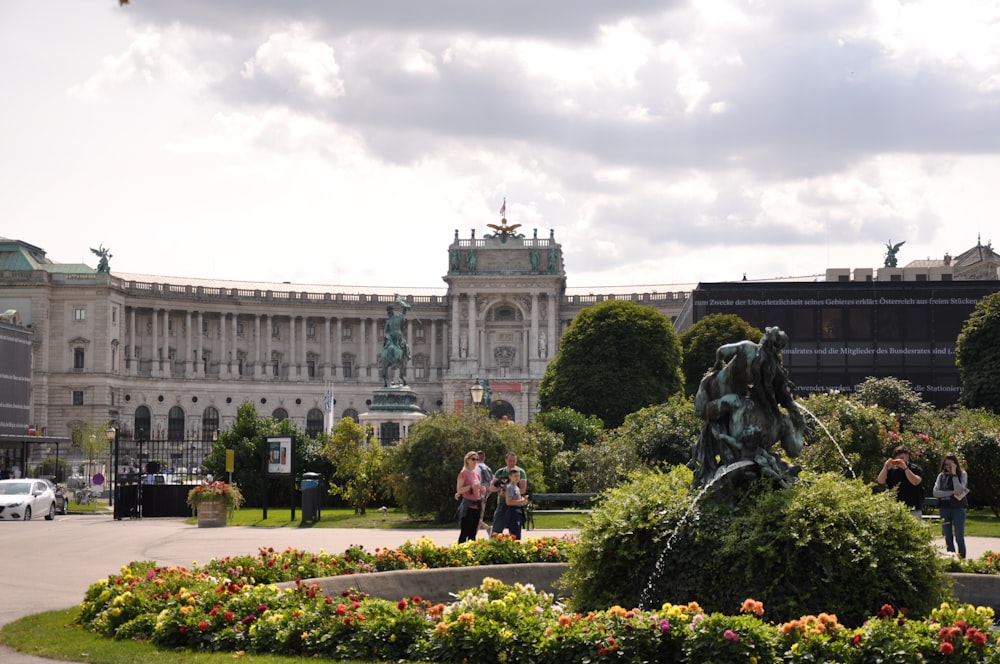 people walking on park with statue of man riding horse statue in front of building during