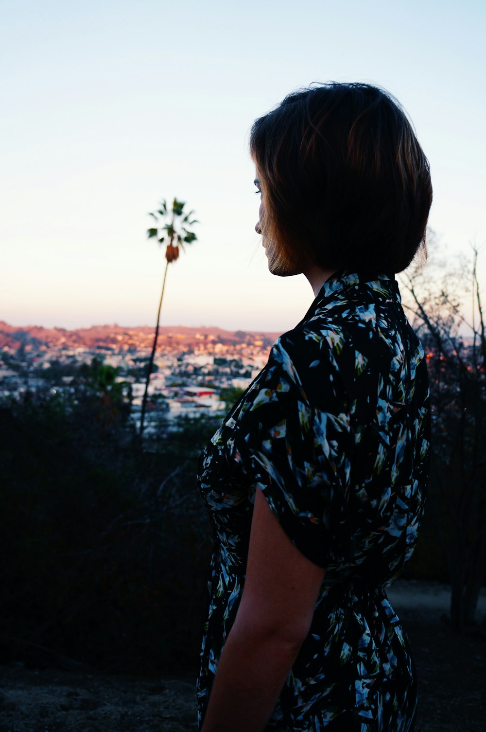 woman in black and white floral shirt standing on grass field during daytime