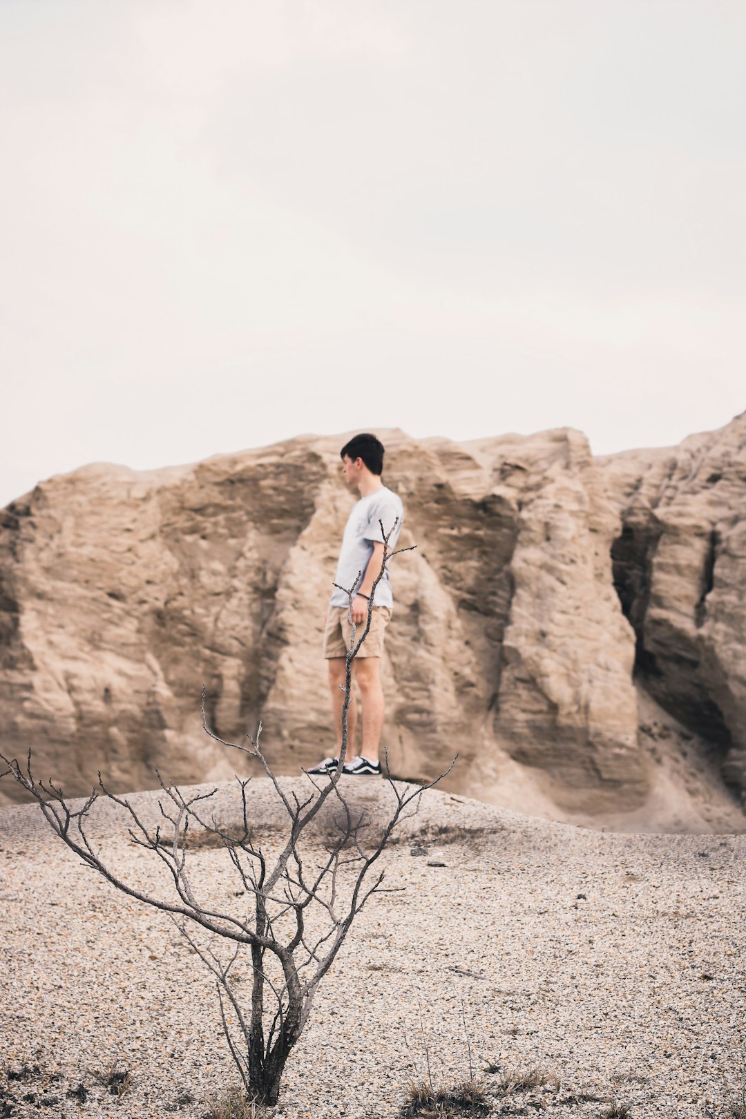 man in white t-shirt standing on brown rock formation during daytime