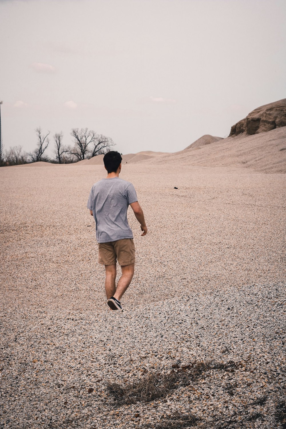 man in white t-shirt walking on brown field during daytime