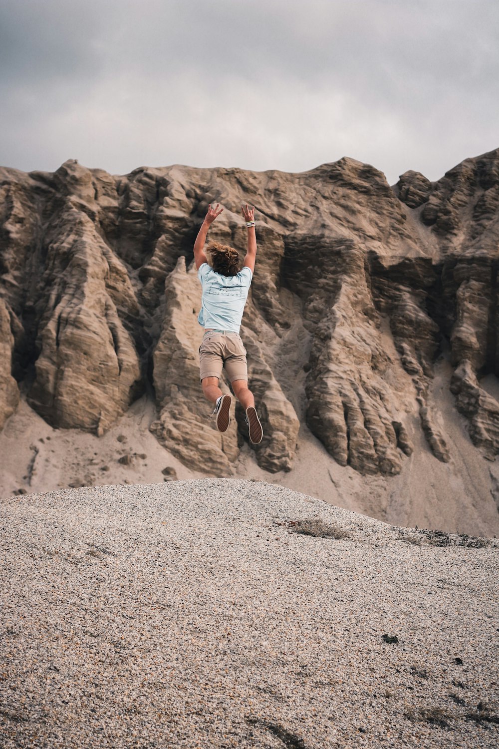 woman in white shirt and brown shorts standing on brown rock formation during daytime