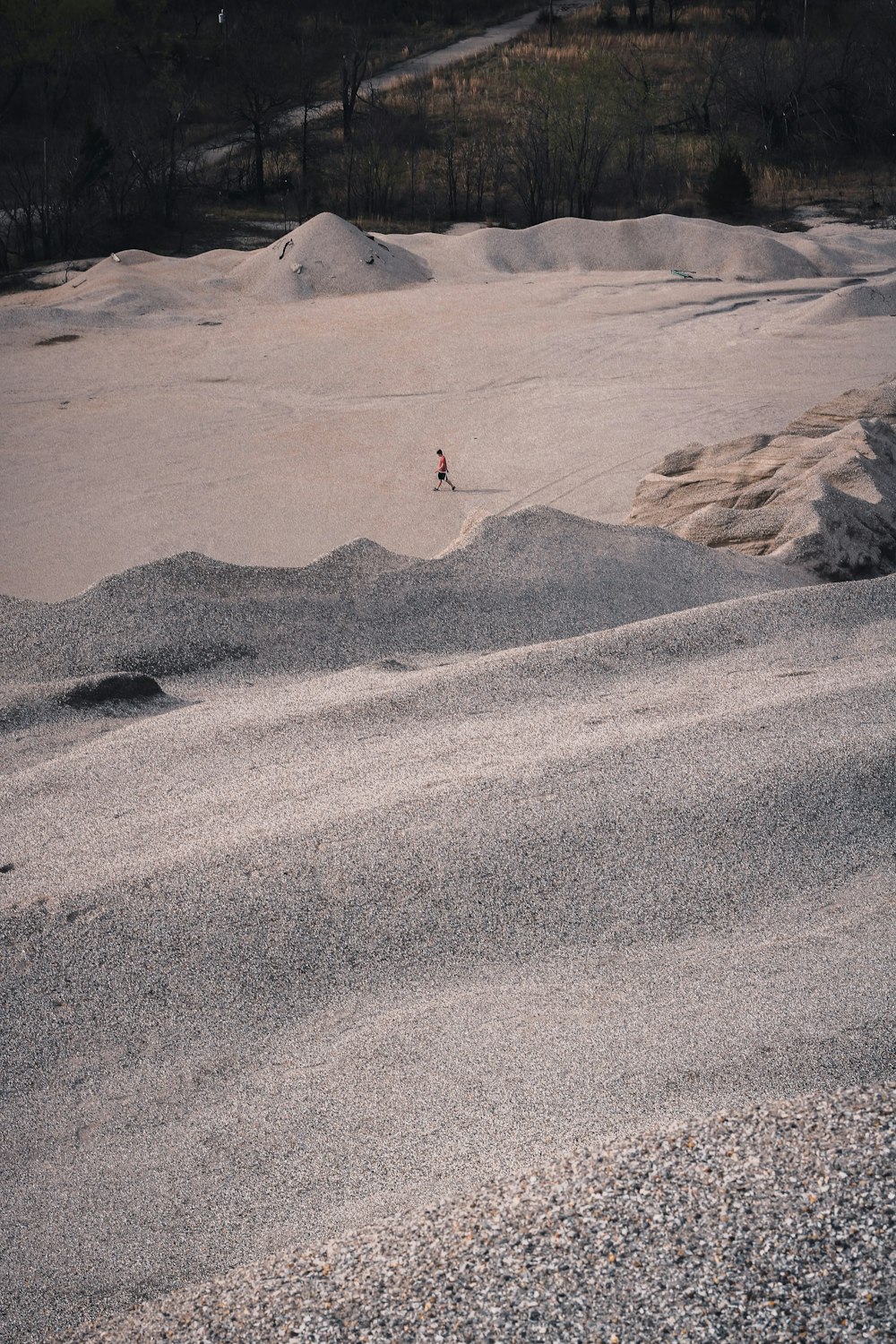person in red jacket walking on gray sand during daytime