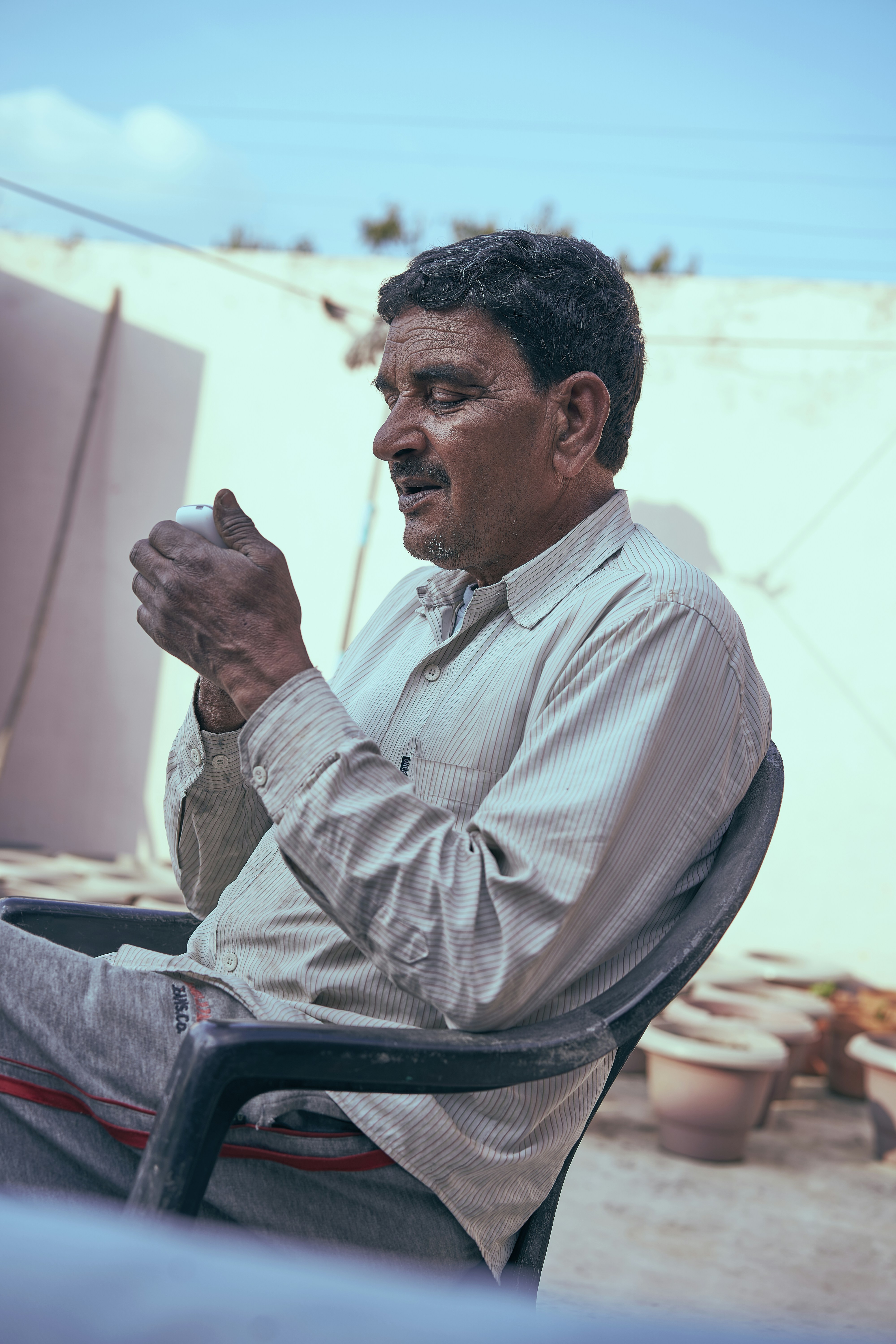 man in white and pink pinstripe dress shirt sitting on chair