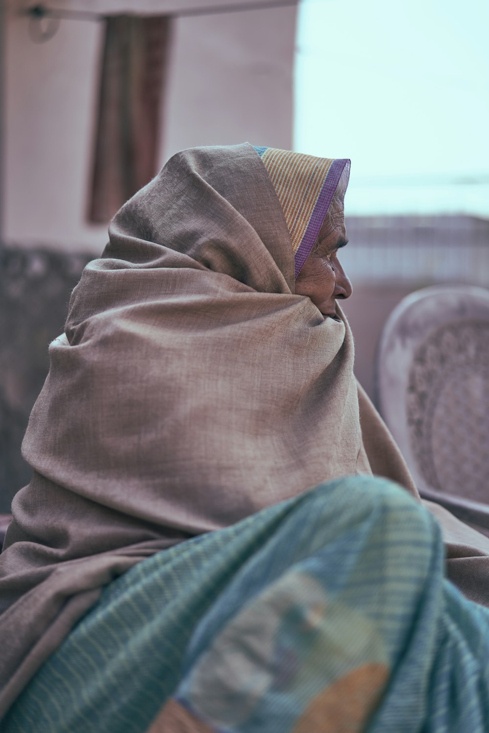 person in brown hijab sitting on white and blue sofa