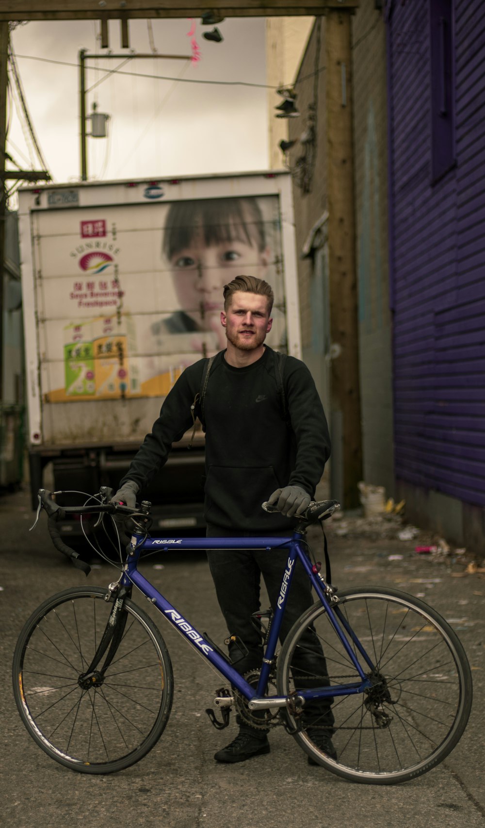 man in black jacket riding on blue bicycle