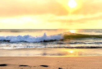Golden hour light casting warm hues on a small island’s white sandy beach surrounded by calm, shallow sea